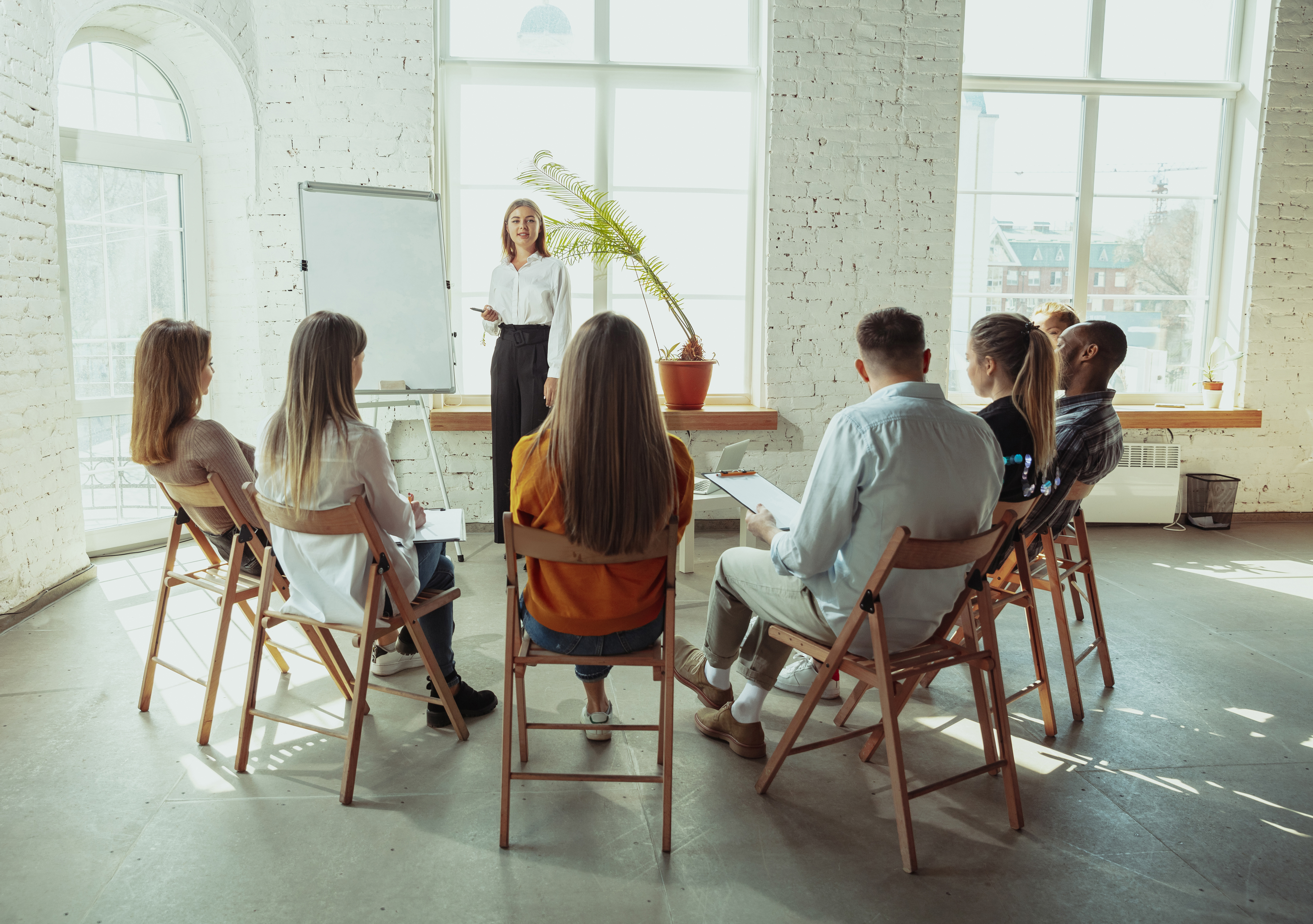 Female caucasian speaker giving presentation in hall at university or business centre workshop